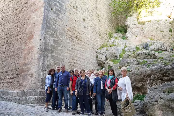 Group of tourists exploring historic stone walls in Óbidos on a private full-day tour from Lisbon, visiting Nazaré, Alcobaça, Batalha, and Fátima.