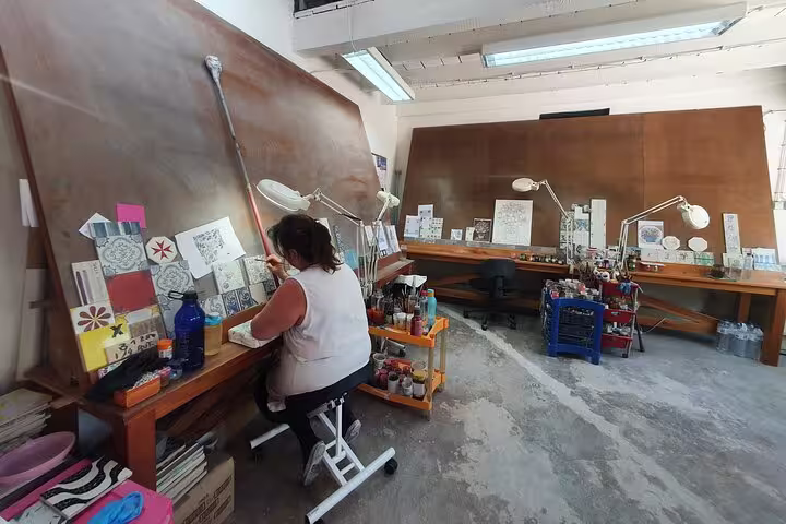 An artisan in a Lisbon workshop creates traditional Portuguese tiles, showcasing local craftsmanship on the Arrábida, Azeitão, Setúbal, and Palmela tour.