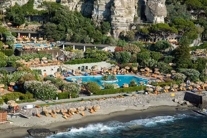 Aerial view of Poseidon Gardens in Ischia, featuring lush greenery, vibrant pools, and scenic beachfront from Naples tour.