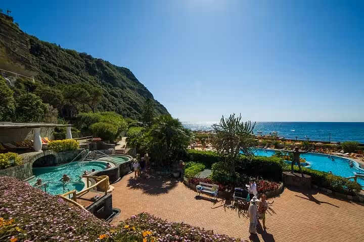 Scenic view of Poseidon Gardens in Ischia with lush greenery, thermal pools, and ocean backdrop on a sunny day.