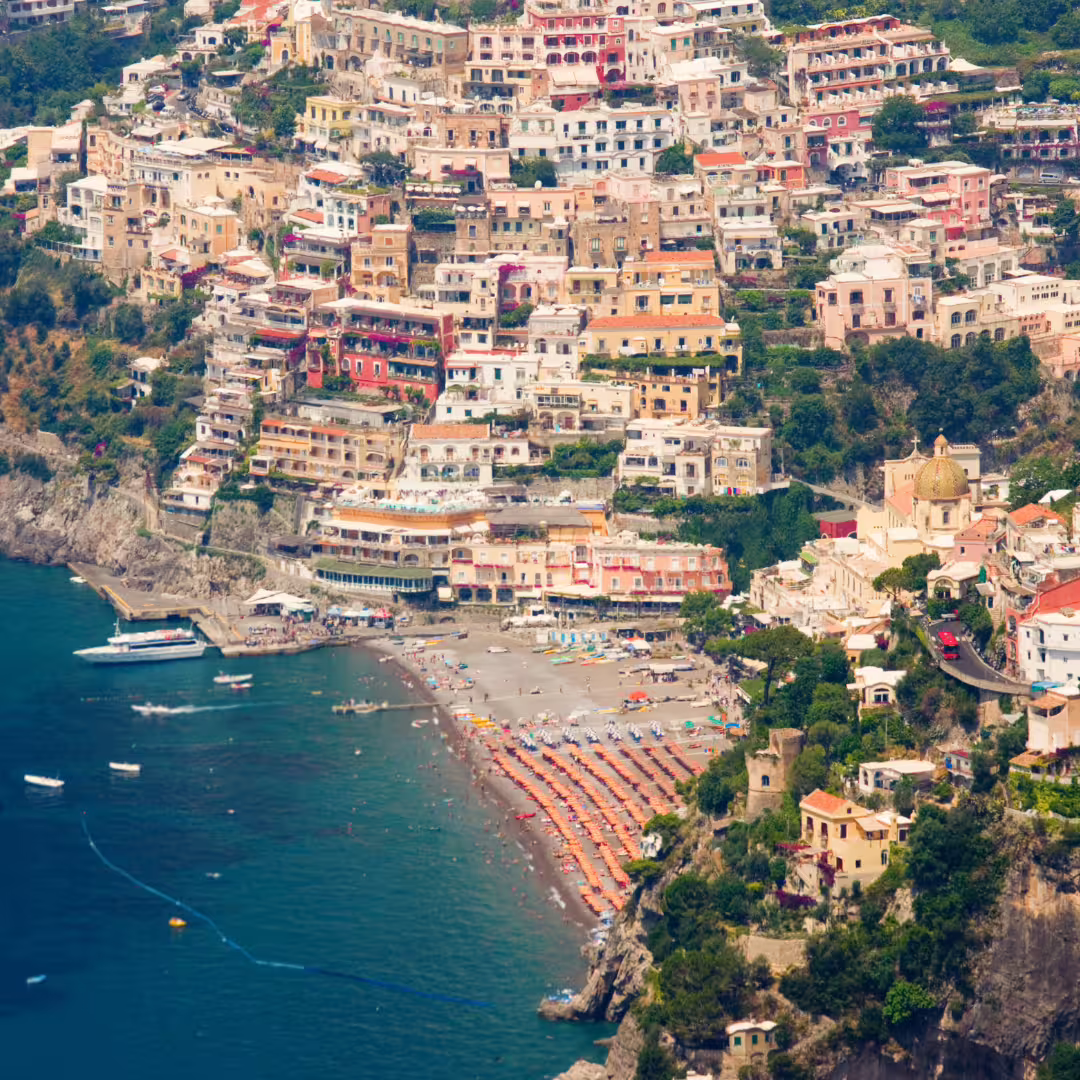 Aerial view of Positano beach and pastel cliffside houses along the Amalfi Coast on the Path of the Gods trek