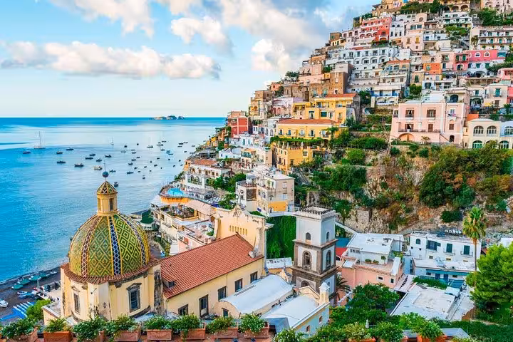 Scenic view of Positano's colorful cliffside buildings overlooking the serene Amalfi Coast on a sunny day.