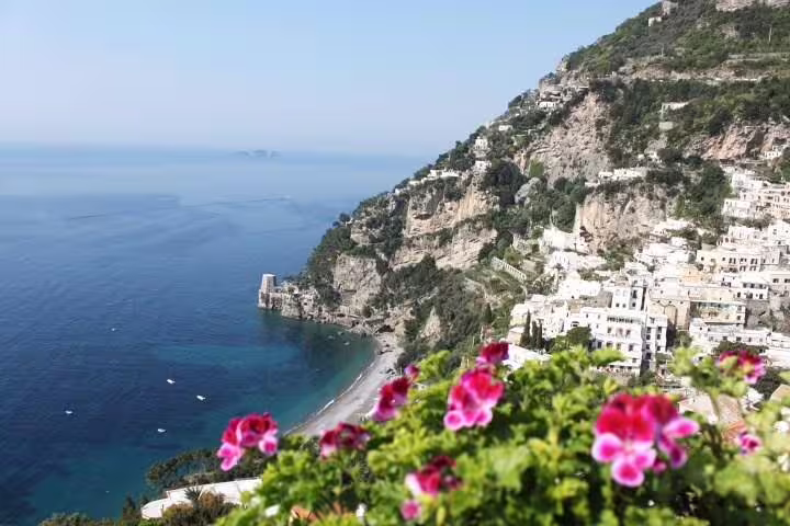 Colorful flowers frame a panoramic view of Positano’s cliffside houses and turquoise Amalfi Coast on a private tour day