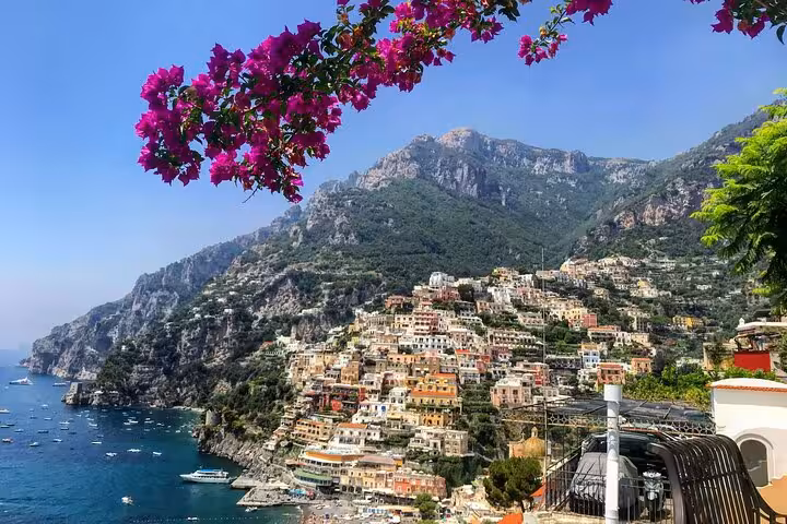 Scenic view of Positano coastline with colorful houses and vibrant bougainvillea, perfect for Amalfi tour listings.