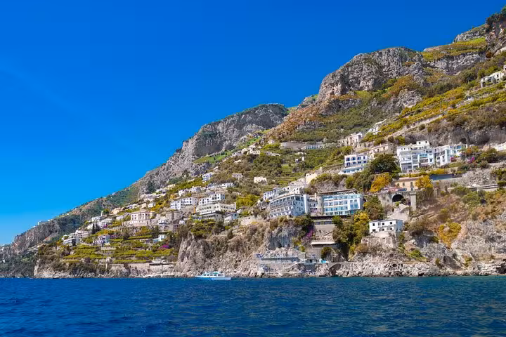 Scenic view of Positano's cliffside homes from a private Gozzo boat tour on the Amalfi Coast under a clear blue sky.