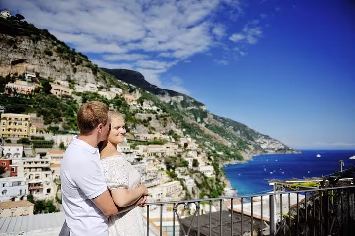 Couple enjoying romantic view of Positano's terraced cliffs and azure sea on an Amalfi Coast excursion.