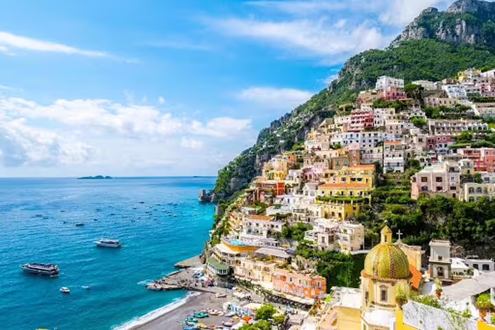 Positano shore excursion panorama on the Amalfi Coast with colorful cliffside villas, beach, and boats on bright blue Mediterranean