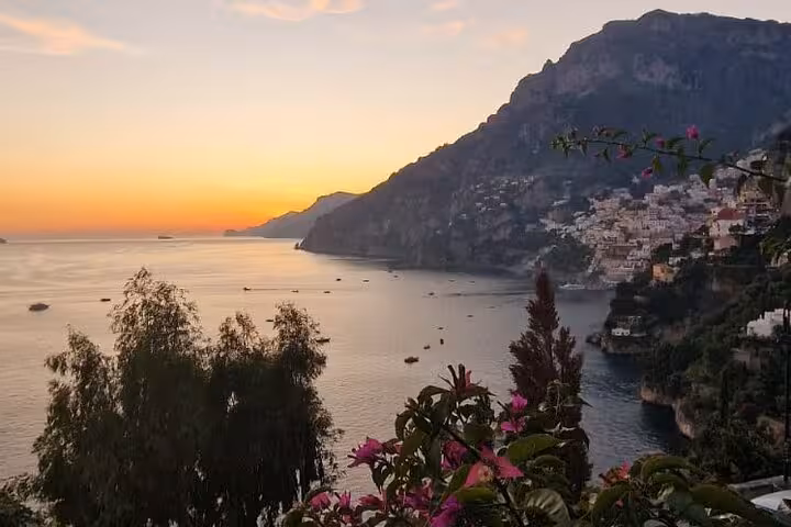 Breathtaking sunset over the Amalfi Coast with Positano in the distance, ideal for a private tour from Naples.