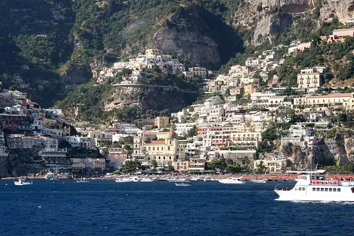 Boats cruising below colorful cliffside houses in Positano, a highlight stop on a private full day Amalfi Coast tour