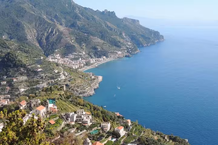 Scenic view of Positano coastline with lush hills and turquoise sea, perfect for private transfer to Rome tours.