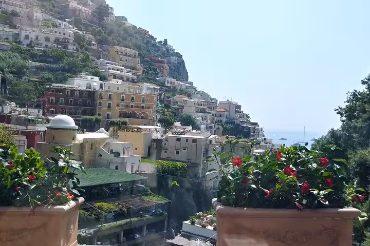 Positano hillside houses and sea view framed by flower pots, on Rome day trip to Amalfi Coast