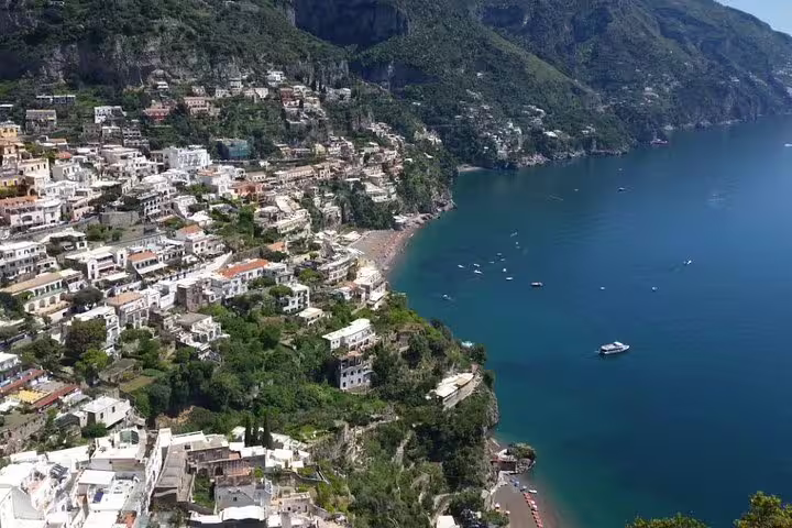 Clifftop view of Positano’s colorful hillside houses and boats on the Amalfi Coast during shared Sorrento Pompeii tour