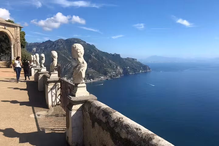 Elegant terrace with statues overlooking Positano's stunning coastal cliffs, ideal stop on way from Positano to Rome.