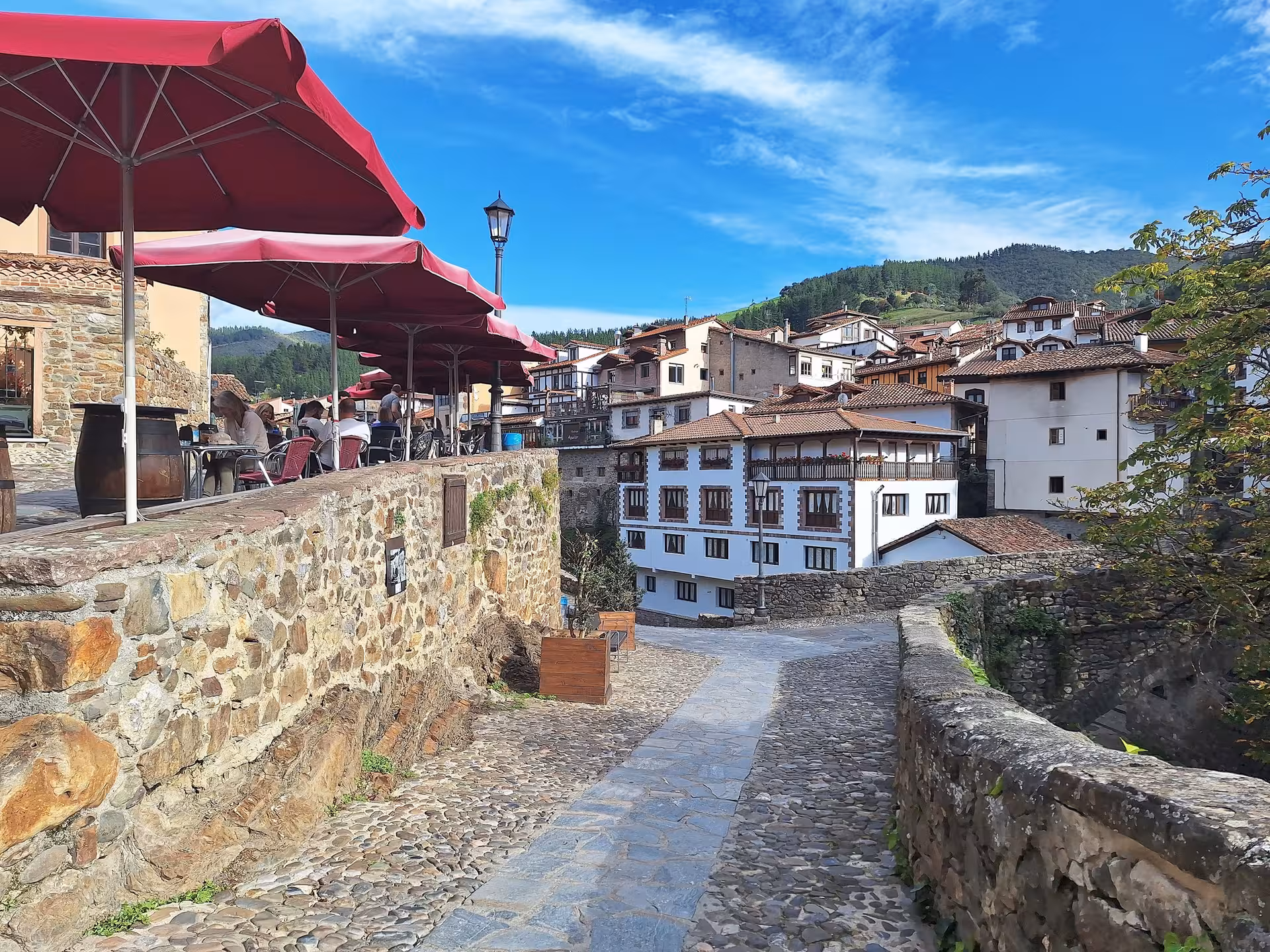 Charming cobblestone street with red umbrellas and historic architecture in Potes, ideal for Picos de Europa tours.