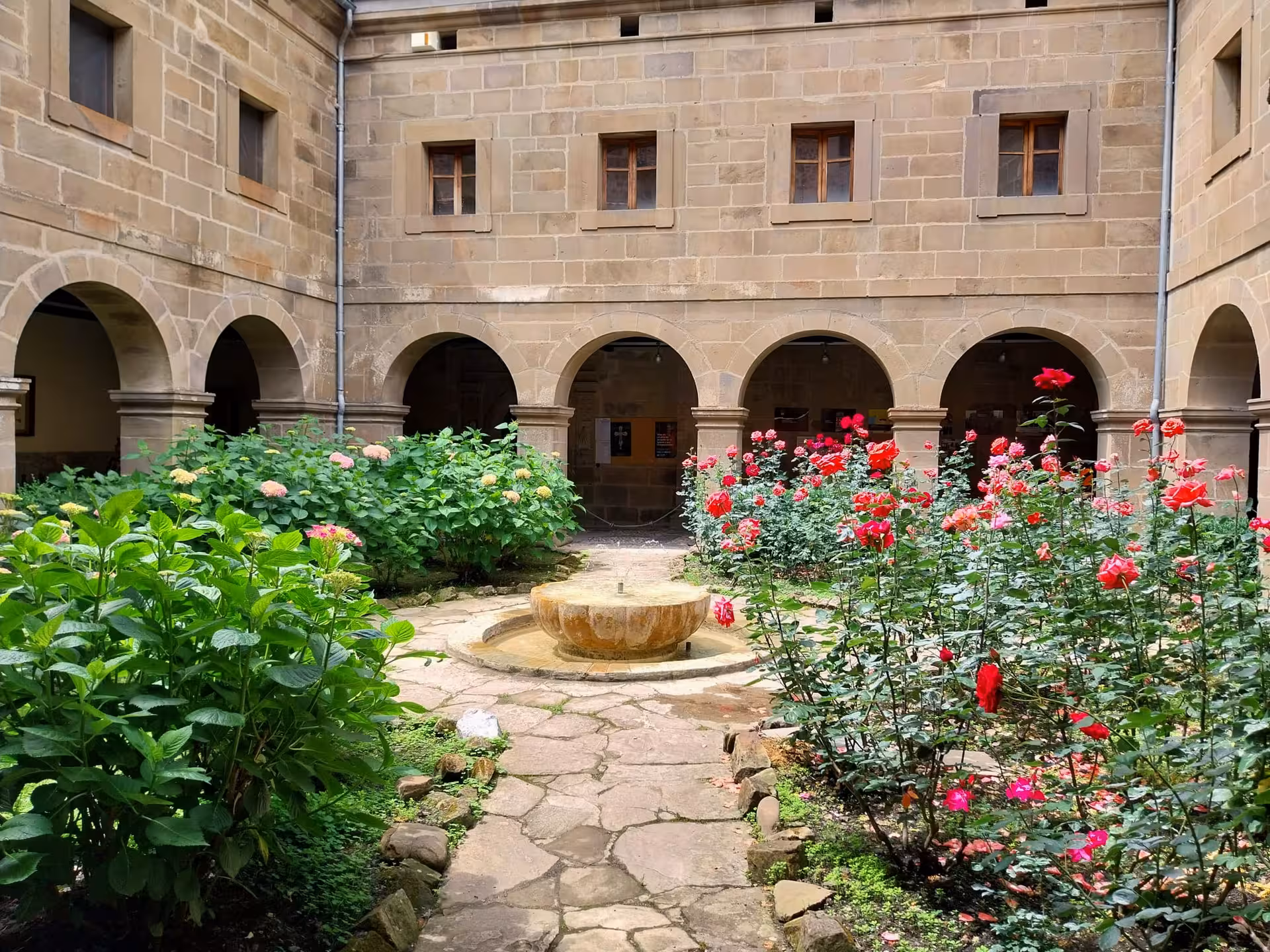 Charming courtyard with blooming red roses and ancient arches in a historic building in Potes, Spain.