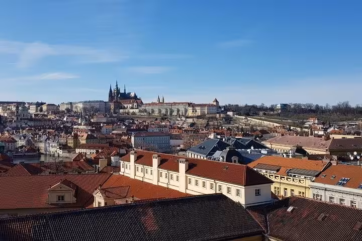 Prague Castle skyline above red rooftops, highlight stop on Vienna to Prague small-group day tour