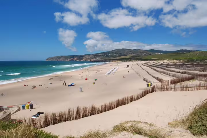 Scenic view of Praia da Adraga beach in Sintra-Cascais Natural Park with soft sand and clear blue waters.