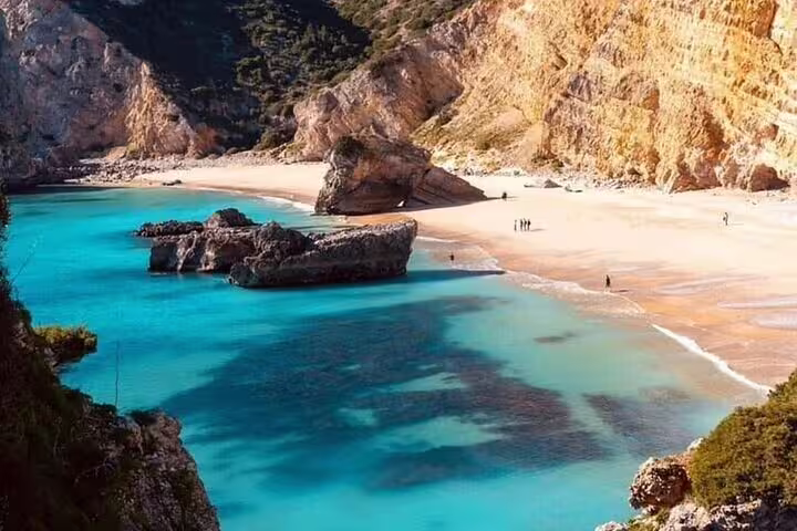 Breathtaking view of secluded Praia da Ribeira do Cavalo with turquoise waters and dramatic cliffs near Setúbal.