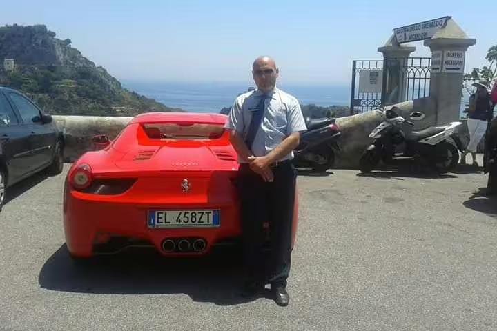 Professional driver standing by red sports car overlooking Amalfi Coast, promoting stylish Praiano to Naples private transfer