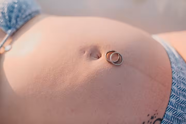 Close-up of pregnant belly with rings, part of a private maternity photoshoot in Gouves.