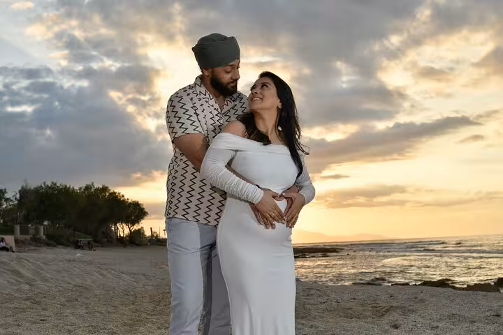 Pregnant couple sharing a tender moment at sunset on Heraklion beach, perfect for a maternity photoshoot.