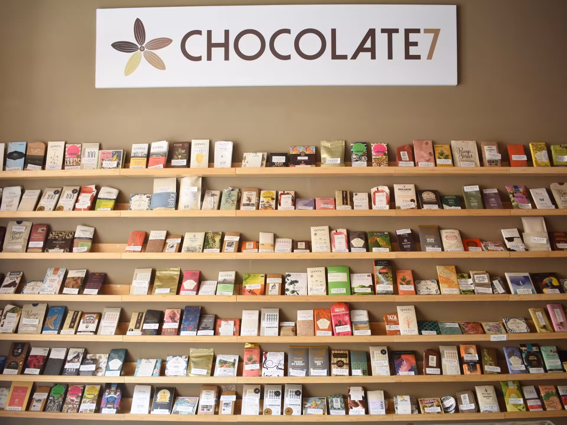 A variety of premium chocolate bars displayed on wooden shelves at a Turin tasting shop.