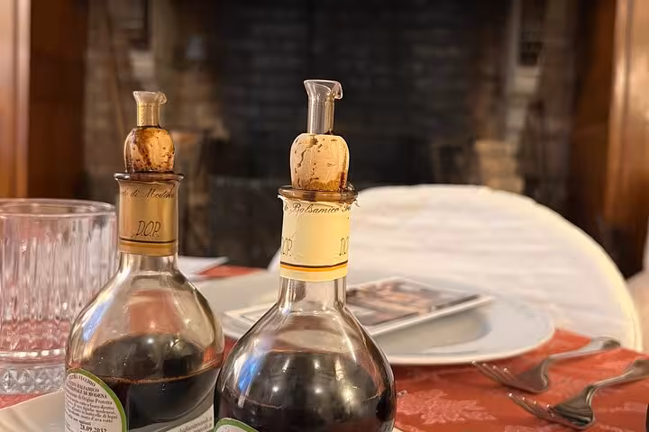 Two bottles of premium DOP balsamic vinegar on a dining table set for tasting.