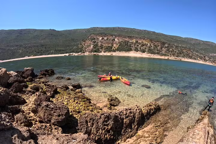 Kayakers enjoy a serene coastal view with clear waters and rocky shores near Lisbon.