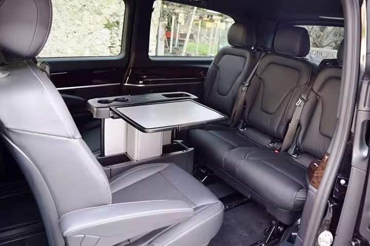 Spacious leather interior of premium minivan used for private transfer from Rome to Amalfi, with recliner seats and table