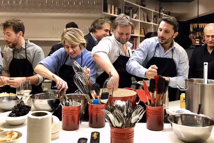 Participants enthusiastically cooking paella in a chic Spanish kitchen setting during a premium cooking class.