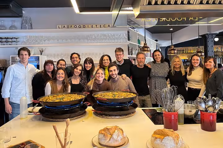 Group of happy participants showcasing their freshly cooked paella during a premium Spanish cooking class.