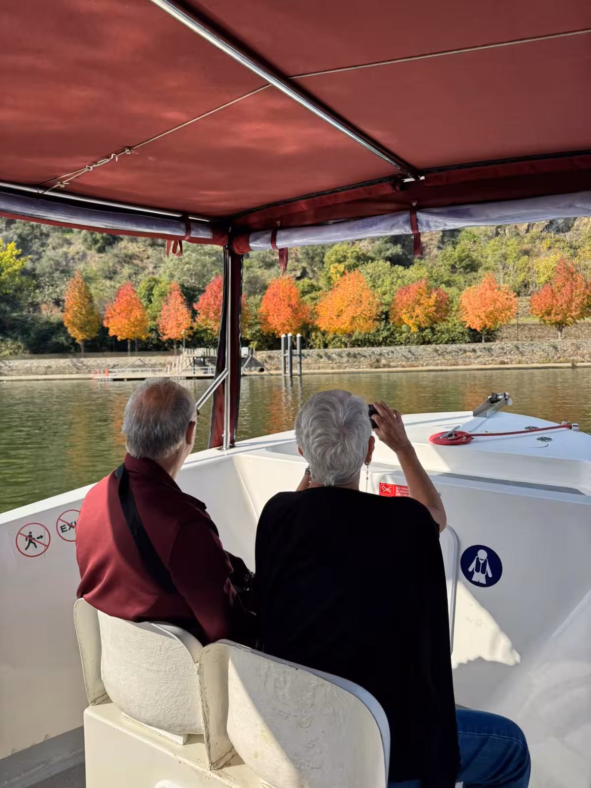 Prestige Tour river cruise with guests photographing vibrant autumn trees along a calm scenic shoreline