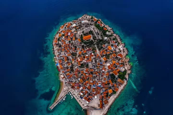 Aerial view of Primošten old town peninsula and turquoise Adriatic sea, perfect beach shore excursion Croatia