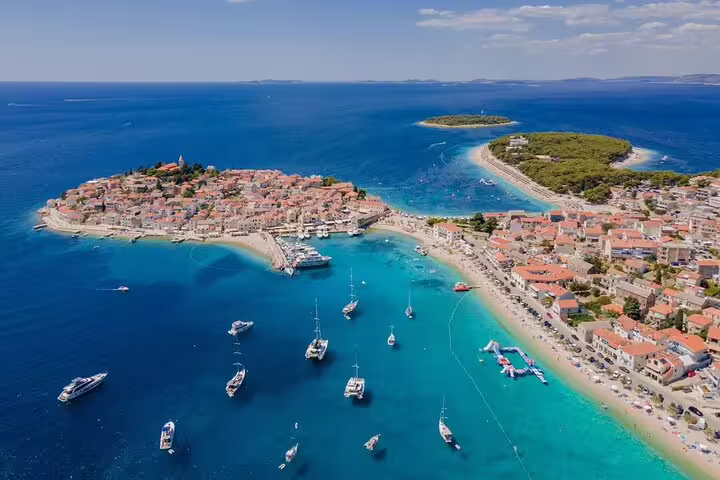 Drone panorama of Primosten Beach with boats in the bay and old town, perfect Croatia shore excursion view