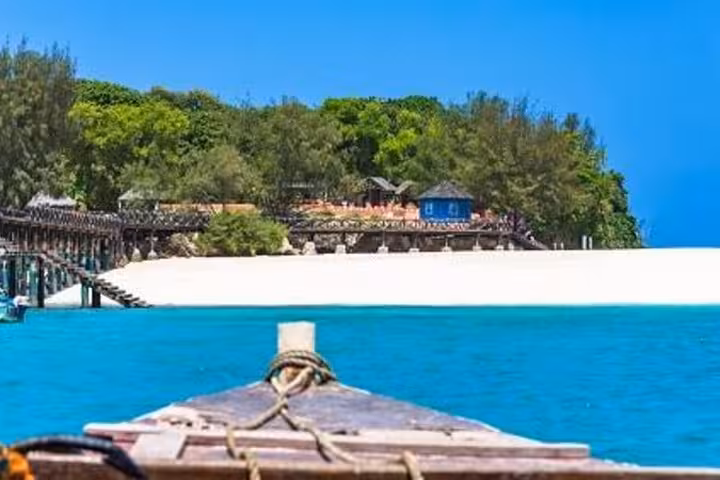 Boat approaching the pristine shores of Prison Island, with lush greenery and clear blue waters in Zanzibar.