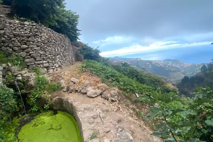 Rocky hillside trail with stone wall and coastal views, scenic stop on a private 4x4 shore excursion adventure
