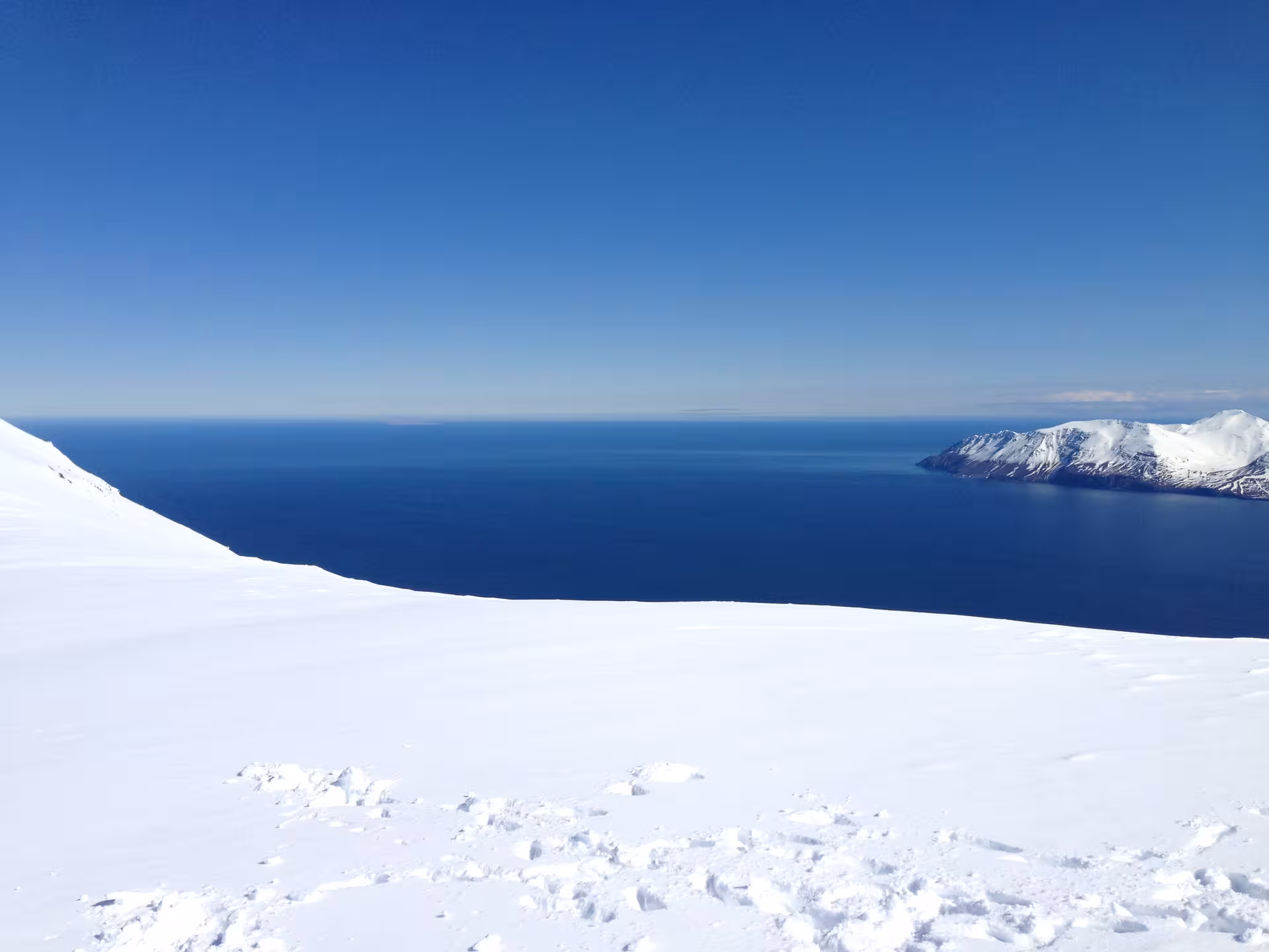 Pristine Arctic coastline with snowy landscape and clear blue skies, ideal for private Arctic tours and exploration.