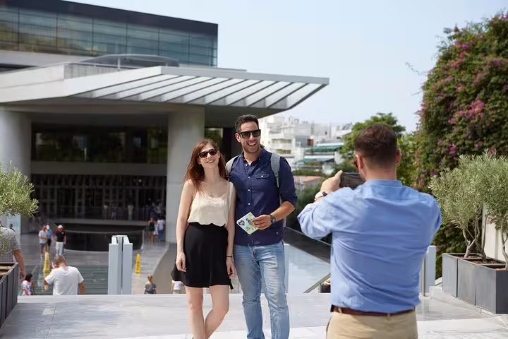 Couple posing for a photo during a private half-day Athens sightseeing ride near a modern city landmark