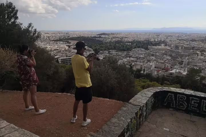 Guests photographing sweeping Athens skyline from a hilltop viewpoint during a private full-day Athens tour
