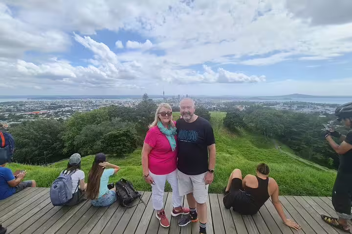 Tourists posing with Auckland cityscape in the background, highlighting the vibrant private day tour experience.