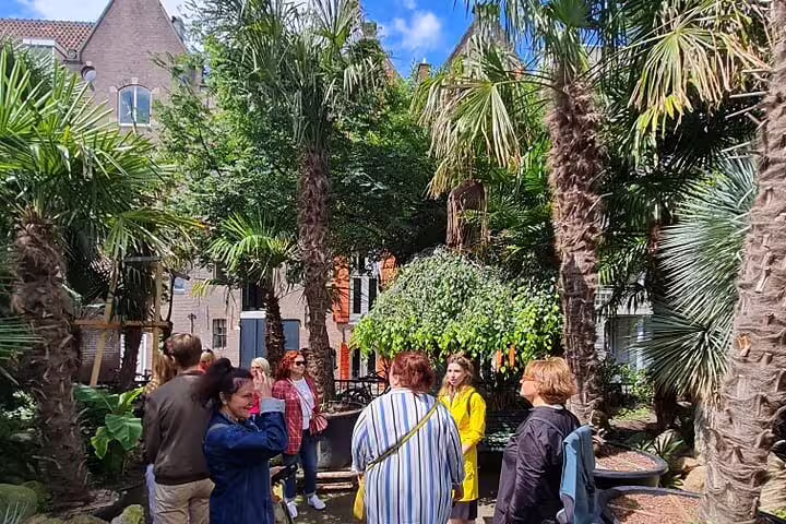 Small group exploring a leafy courtyard on a private bike tour discovering hidden gems around Amsterdam