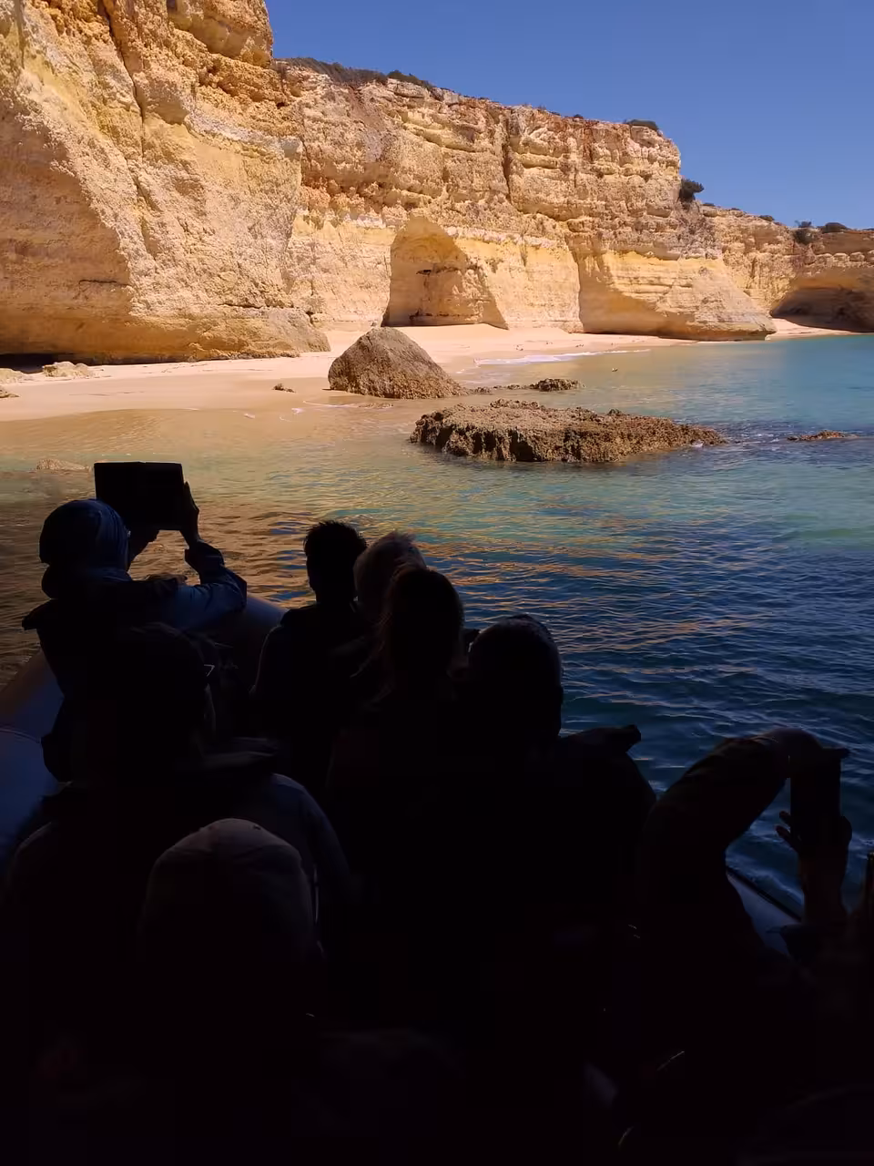Guests on a private boat charter from Albufeira cruising past Algarve cliffs and a secluded sandy cove