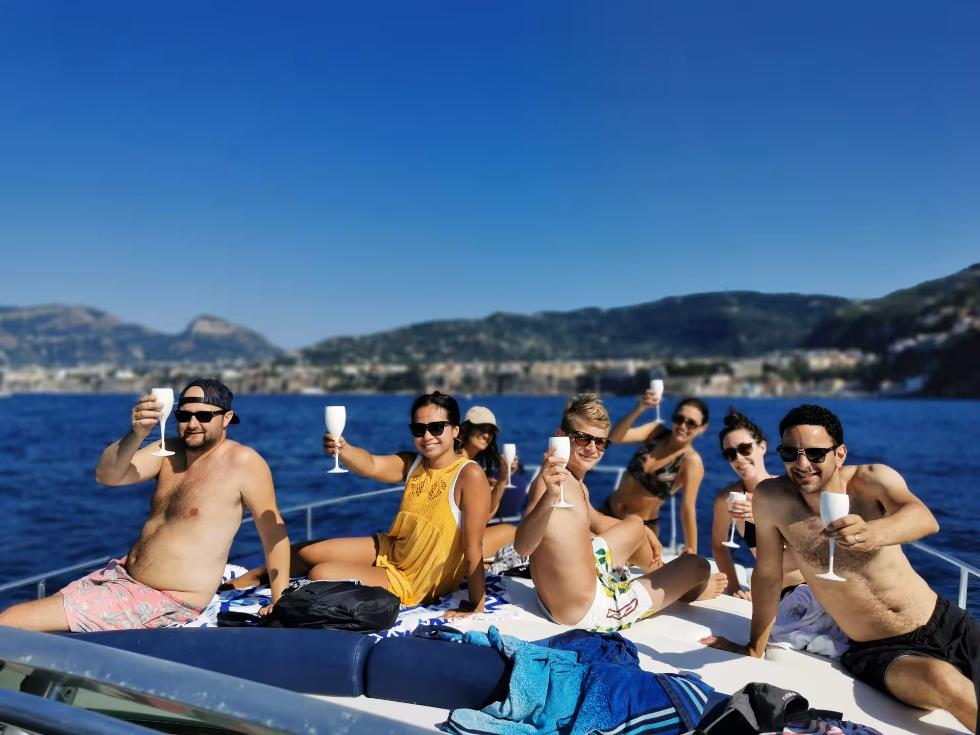 Group of friends toasting with drinks under the sun on a private boat tour along the Amalfi Coast.