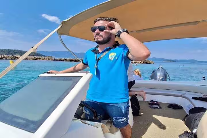 Man steering a private boat on a sunny Angra & Ilha Grande tour with clear blue waters and distant islands.