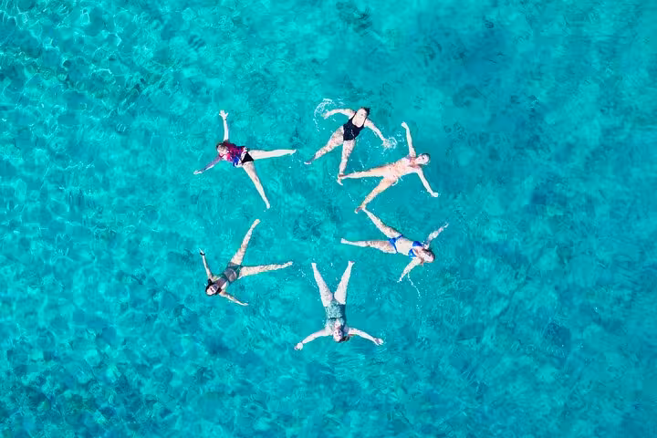 Aerial view of friends floating in crystal-clear Adriatic water on a private boat tour in Croatia