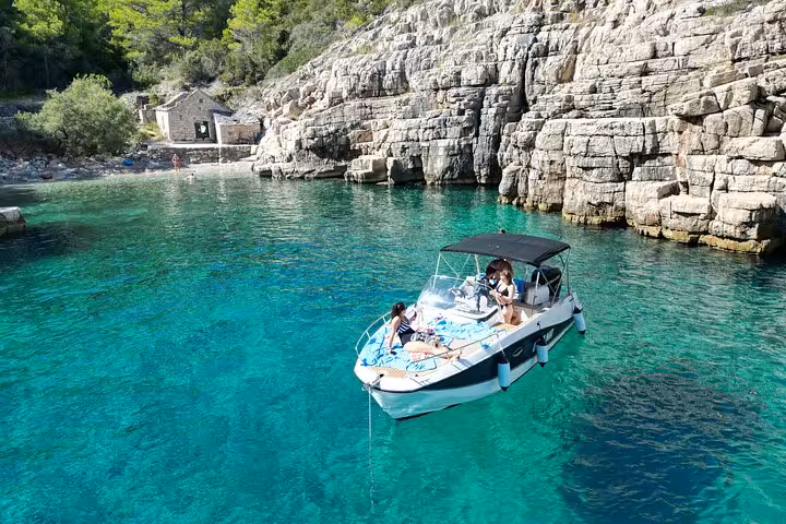 Private boat anchored in a turquoise Croatian cove by rocky cliffs, perfect for swimming and snorkeling tour