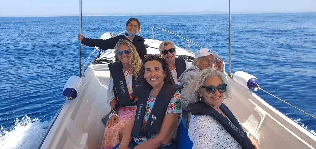 Group enjoying a sunny day on a private boat tour in Ria Formosa, wearing life jackets and smiling.