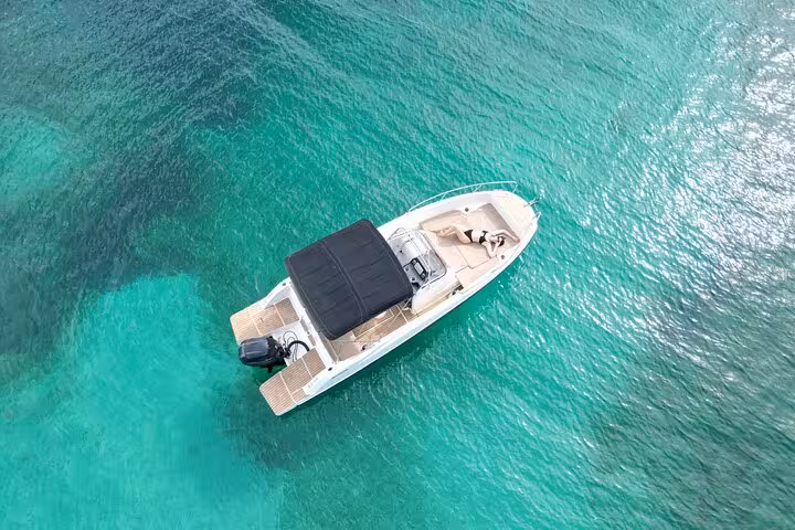 Aerial view of a private boat on clear turquoise waters, ideal for San Antonio tours with paddle surfing and snorkeling.