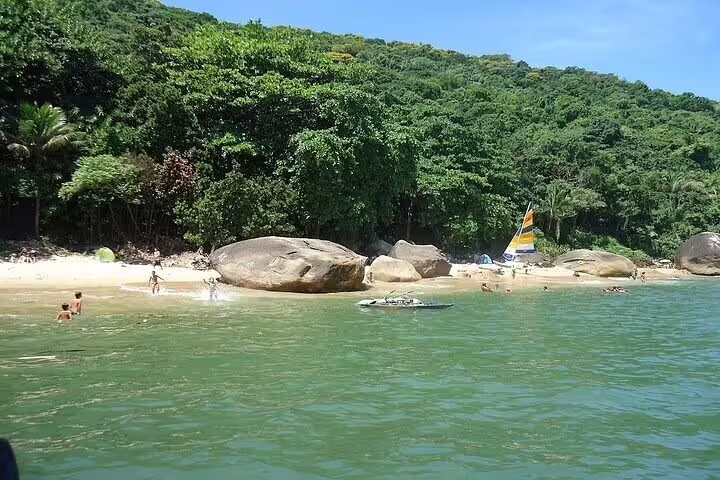 Tranquil beach with lush greenery and clear waters, perfect for a private boat tour in Santos with barbecue.
