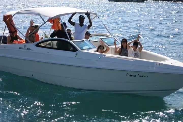 Guests waving and toasting on a private boat tour in Santos, enjoying sunlit waters and refreshing drinks on board.